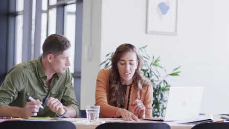 Diverse-male-and-female-colleagues-in-discussion-using-laptop-in-casual-office-meeting