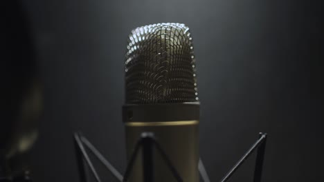 tilt up on voice over microphone in a dark studio recording room