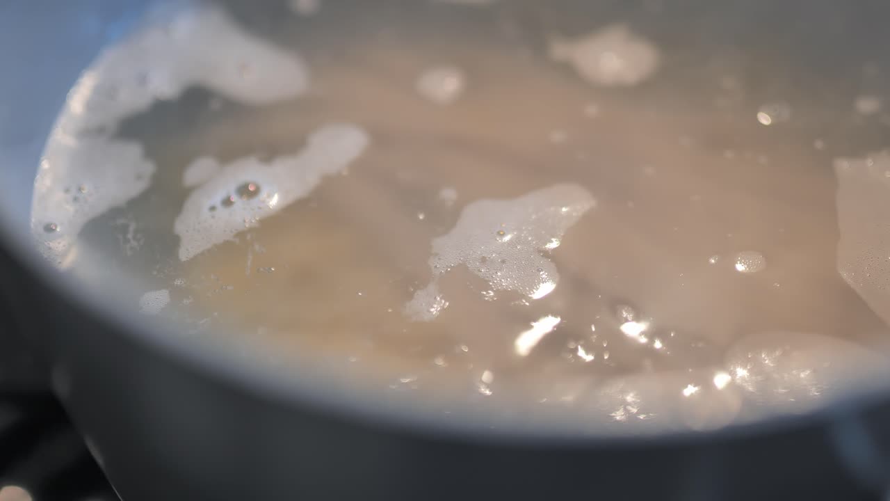 Water boiling in a pot over stove with pasta