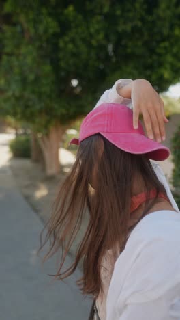 young woman outdoors wearing pink baseball cap