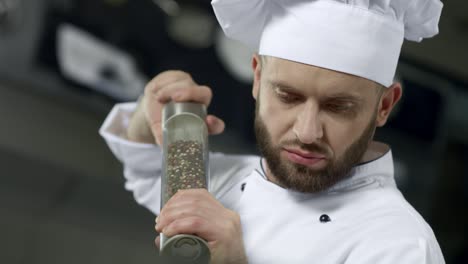 Portrait-of-chef-cooking-at-kitchen.-Closeup-chef-peppering-food-in-slow-motion.