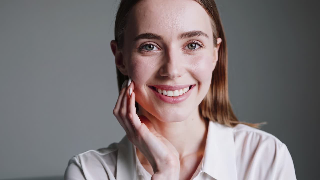 Close-up video of a smiling woman in a white shirt, captured from a front-facing angle