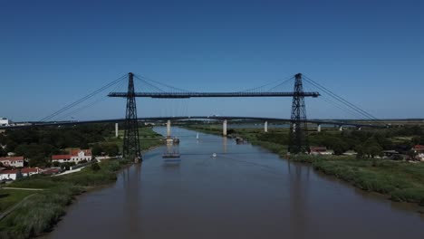 aerial approach of the suspended rochefort bridge while the platform is crossing, france