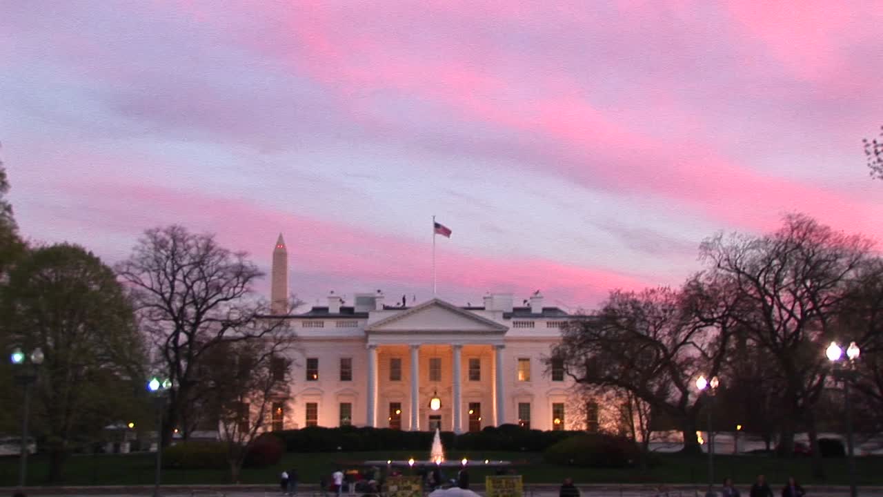옅은 분홍색과 파란색 줄무늬가 백악관 뒤에 화려한 배경을 형성합니다.