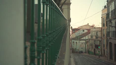 lisbon alfama ancient medieval vintage street with house roofs, railway tram, stone pavement, iron fence, 4k