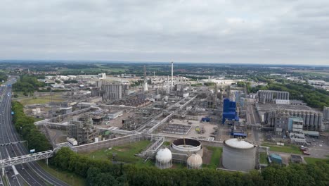 wide drone footage of a massive industrial refinery with tanks, pipes, and production facilities surrounded by infrastructure