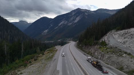 heavy hauler semi truck transporting excavator on coquihalla's steep slope on a overcast day