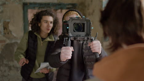 production worker and cameraman closely recording a girlâ€šã„ã´s face during a scene in a ruined building