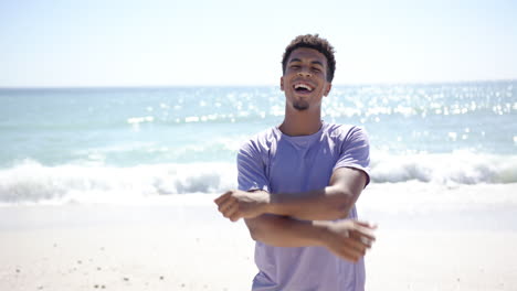 un joven biracial extiende los brazos en una playa soleada con espacio de copia