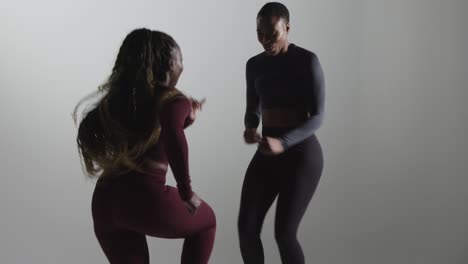 studio shot of two women wearing gym fitness clothing facing each other exercising 7