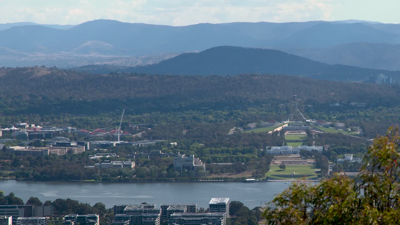 Plano estático y amplio de la ciudad de Canberra, el lago Burley Griffin y el Parlamento a la luz del día