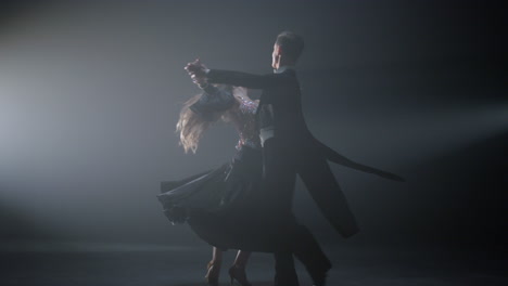 young dance couple performing valse on stage. ballroom dancers twirling around.