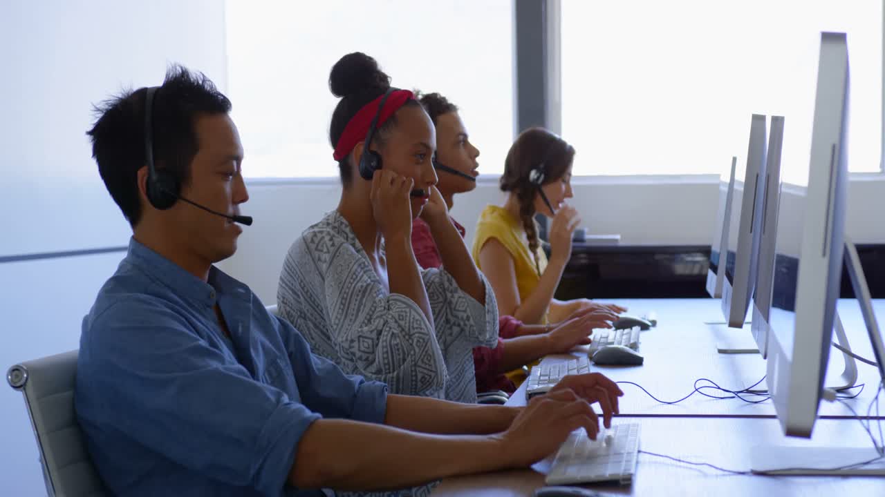 Dirigenti commerciali multietnici che parlano con le cuffie in un ufficio moderno 4K.