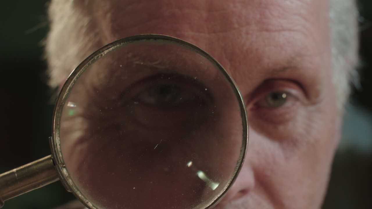 An older man looks through the loupe