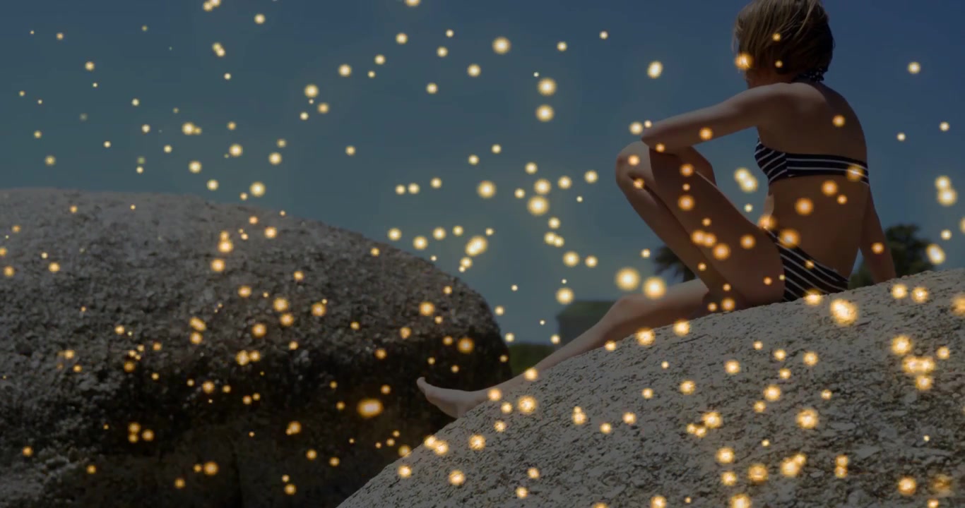 Bambino che entra nell'inquadratura, piega le gambe e guarda l'orizzonte da una roccia, con scintille dorate che fluttuano intorno.