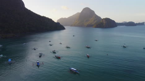 Fliegen-über-Verankerte-Boote-Vor-Hohen-Fernen-Bergen,-El-Nido,-Philippinen