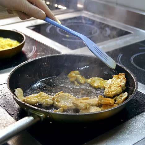 Fillet of sea white fish fried on a pan. Unrecognizible chef mixes dish with spatula. Appetizing and delicious seafood dish