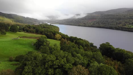 Aerial-View-Of-Over-Green-Valley-River-Bank-With-Loch-Tummel-In-Background