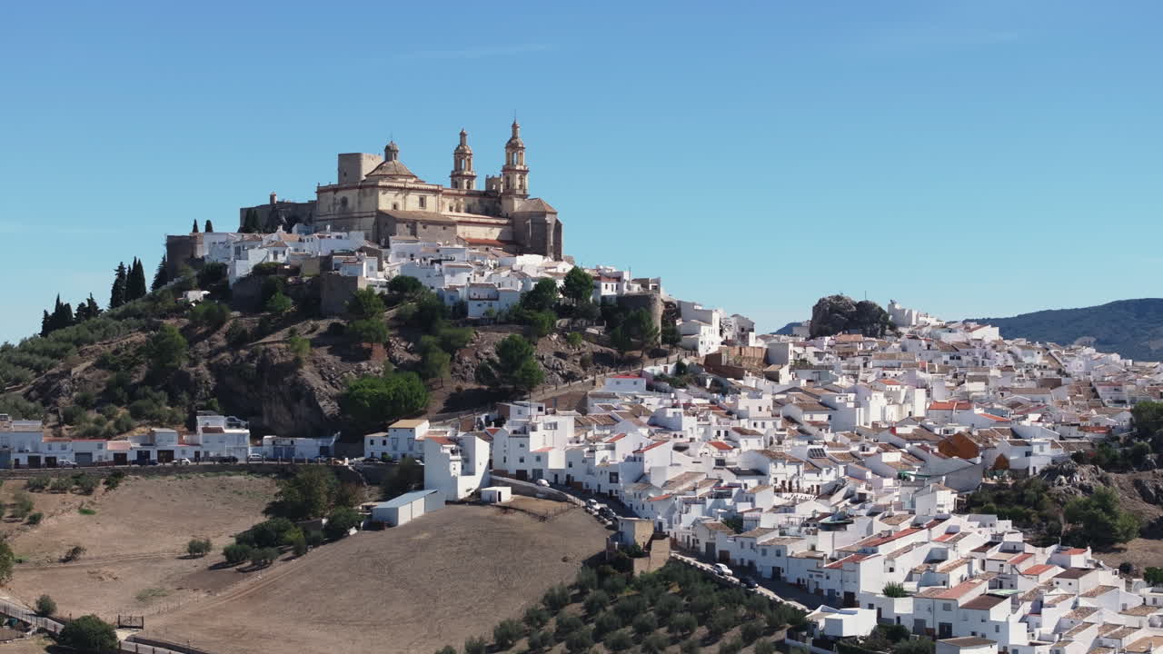Luftdroneoptagelse i bredt panorama af den smukke hvide by Olvera i Andalusien, Spanien, Europa. Traditionelt slot og kirke på en bakke samt oliventræer. Filmisk farvekorrektion