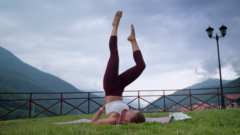 woman practicing headstand yoga pose in a mountain park