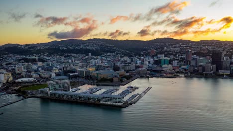 hiperlapso aéreo, puesta de sol sobre la ciudad de wellington, capital de nueva zelanda, cuando el sol comienza a ponerse detrás de las colinas, panorámica a la izquierda