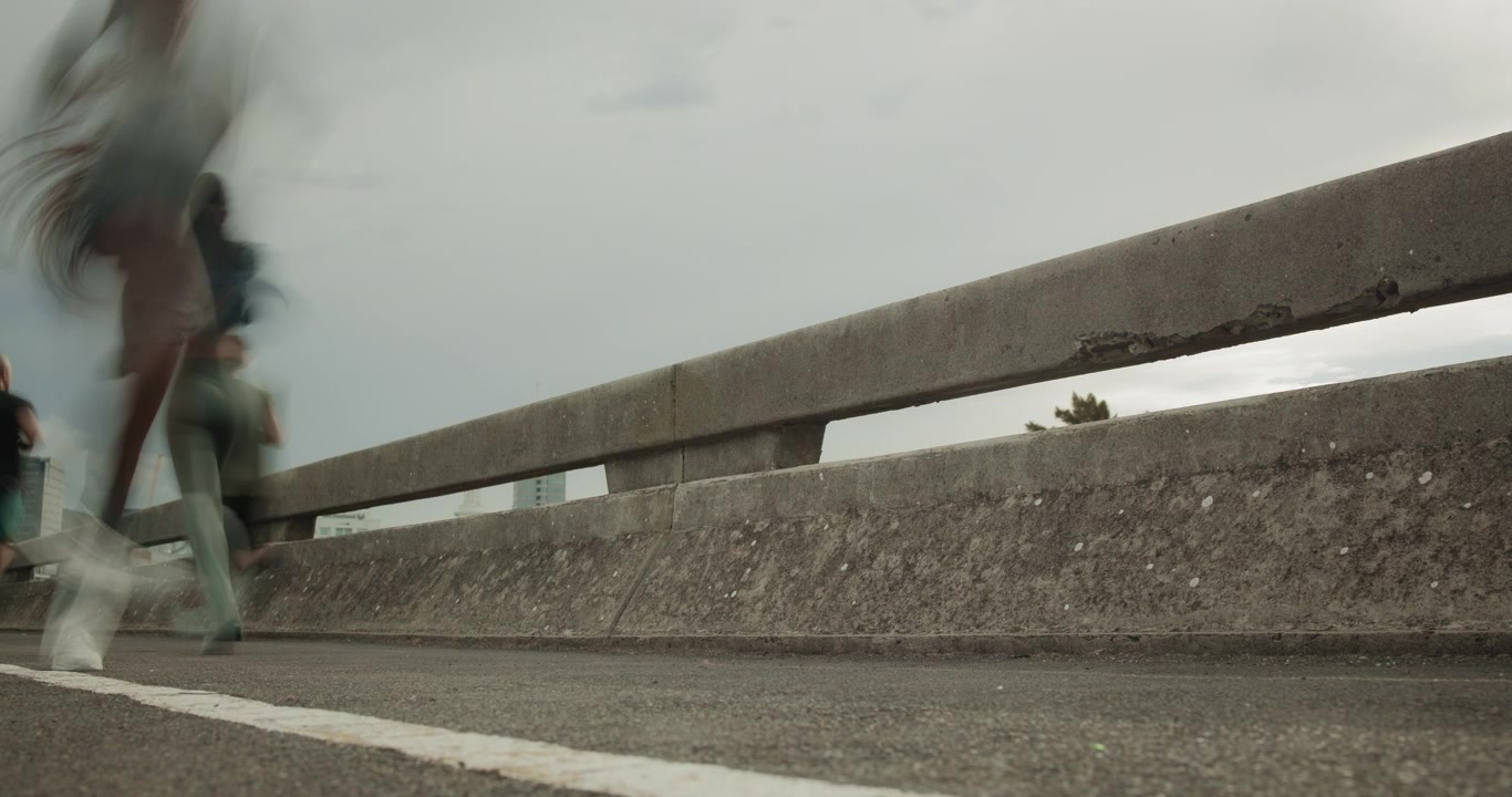 Gruppo di runner che corrono su un ponte urbano in movimento sfocato
