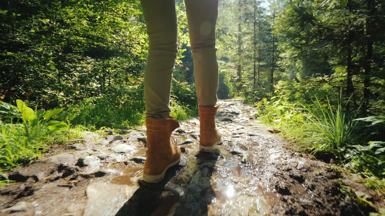 siga el tiro: un hombre con botas de trekking camina por un camino pedregoso resbaladizo en el bosque, caminatas y actividades