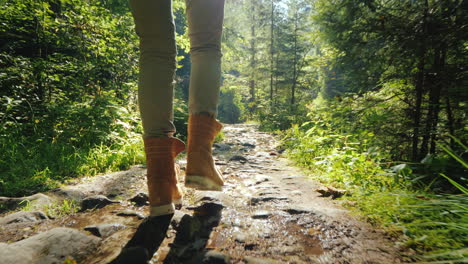 follow shot: a man in trekking boots walks along a slippery stony path in the forest hiking and acti