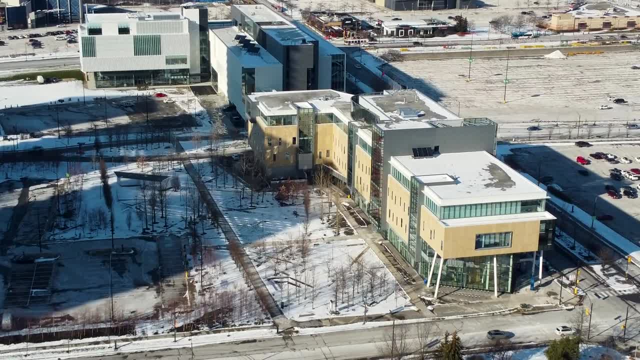 dron volando hacia los edificios del campus universitario cubiertos de nieve