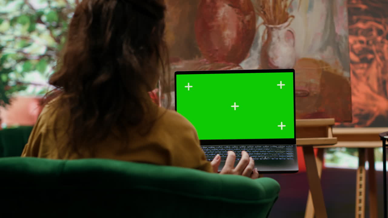 Woman using laptop with green screen in art studio