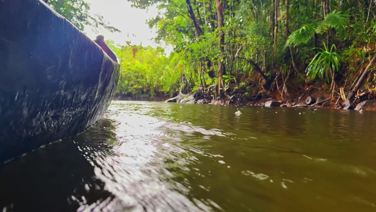 Afrika, Madagaskar'daki Masuala Milli Parkı'na doğru, yağmurda bir Pirogue (el yapımı kano) ile nehir yukarı çıkmak. Pirogue ile nehir kenarlarından açıklığa doğru alternatif yan çekim. 4K.