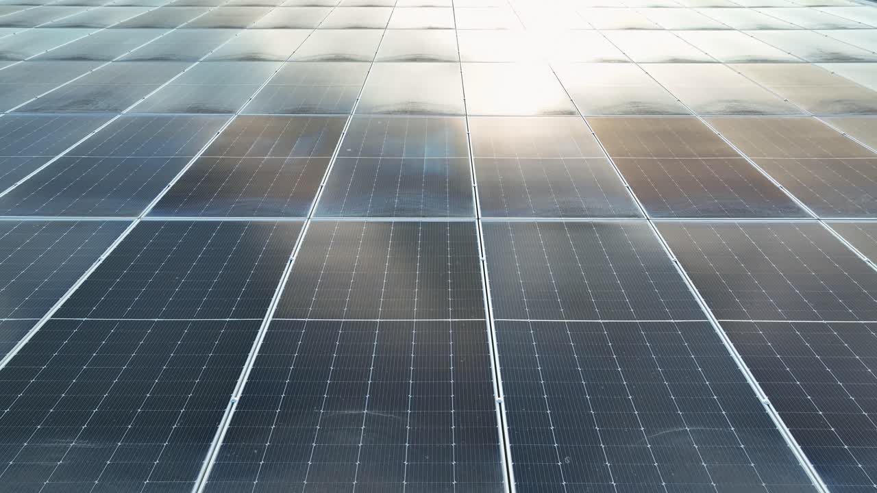 家の屋根にある太陽光パネルユニットに反射する太陽。空撮での接写。現代の再生可能エネルギーをテーマに。