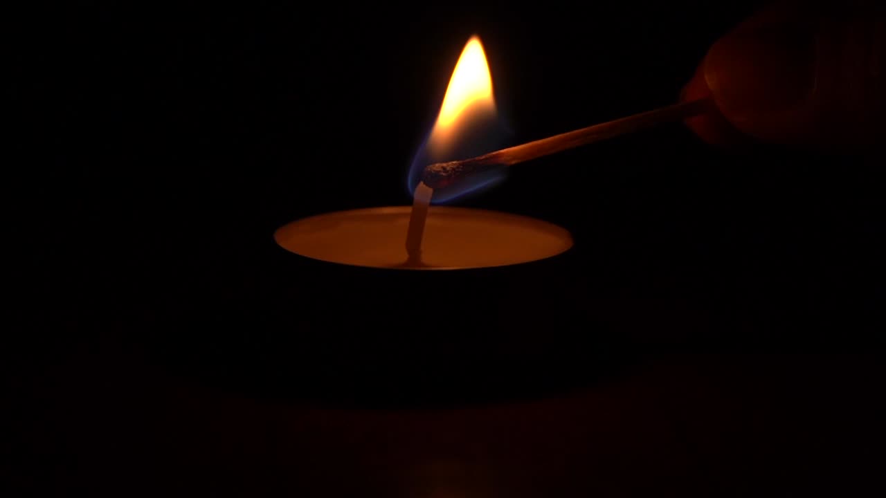 Accendere una candela con un fiammifero nell'oscurità.