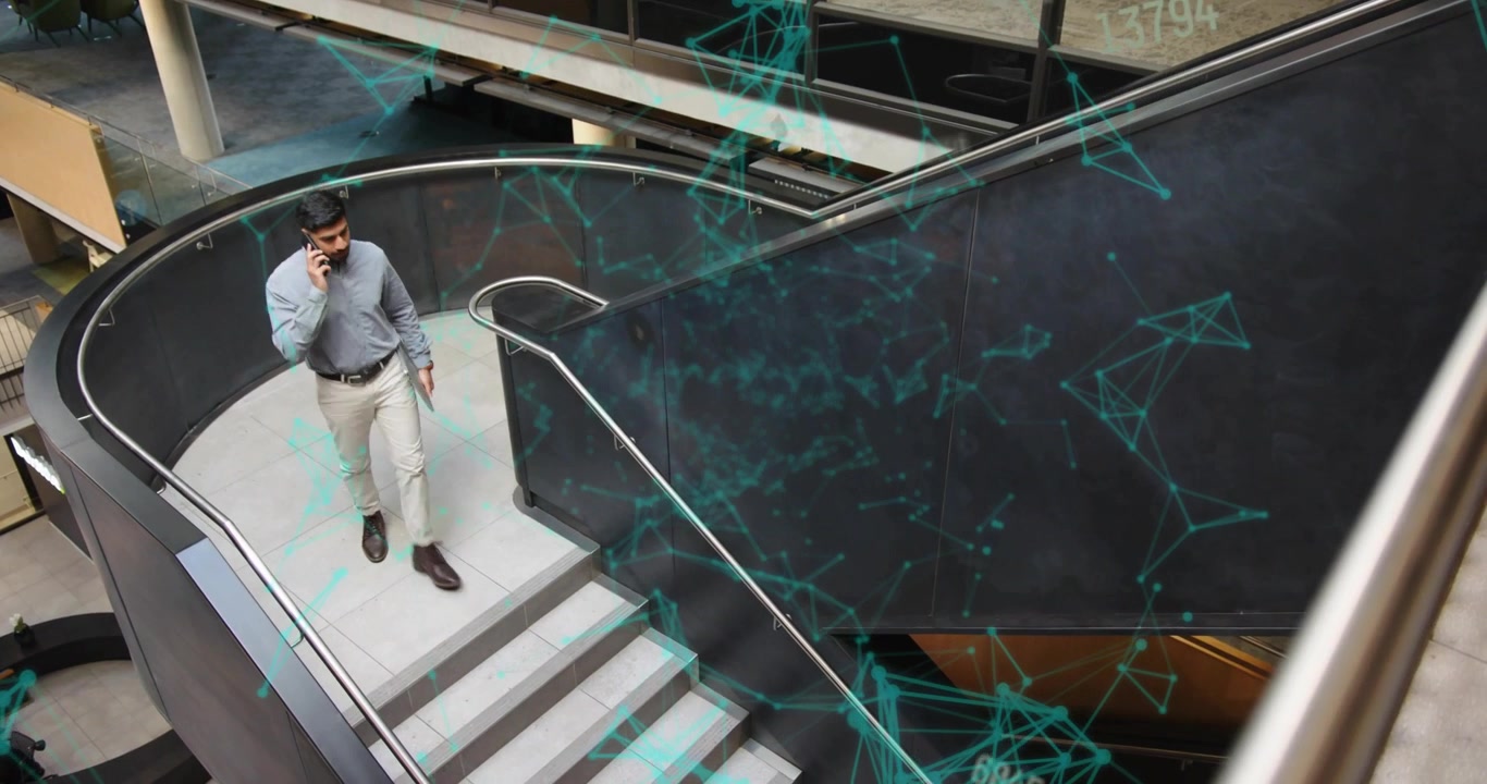 Businessman answering phone call and descending staircase while navigating network numeric overlays