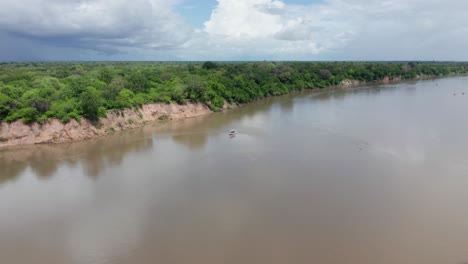 aerial drone shot of a river in selous, tanzania, tilting the camera down pointing to a boat standing still. sunny day
