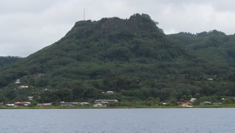 lush green mountain and coastal village with overcast sky