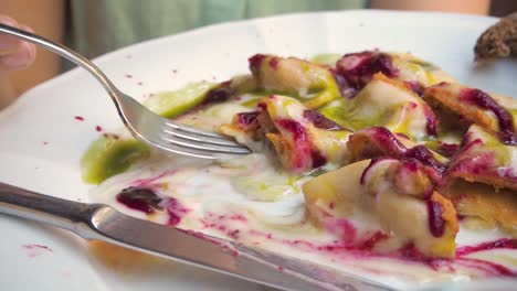4k cerca de mujer comiendo ravioli con salsa de crema colorida y albahaca