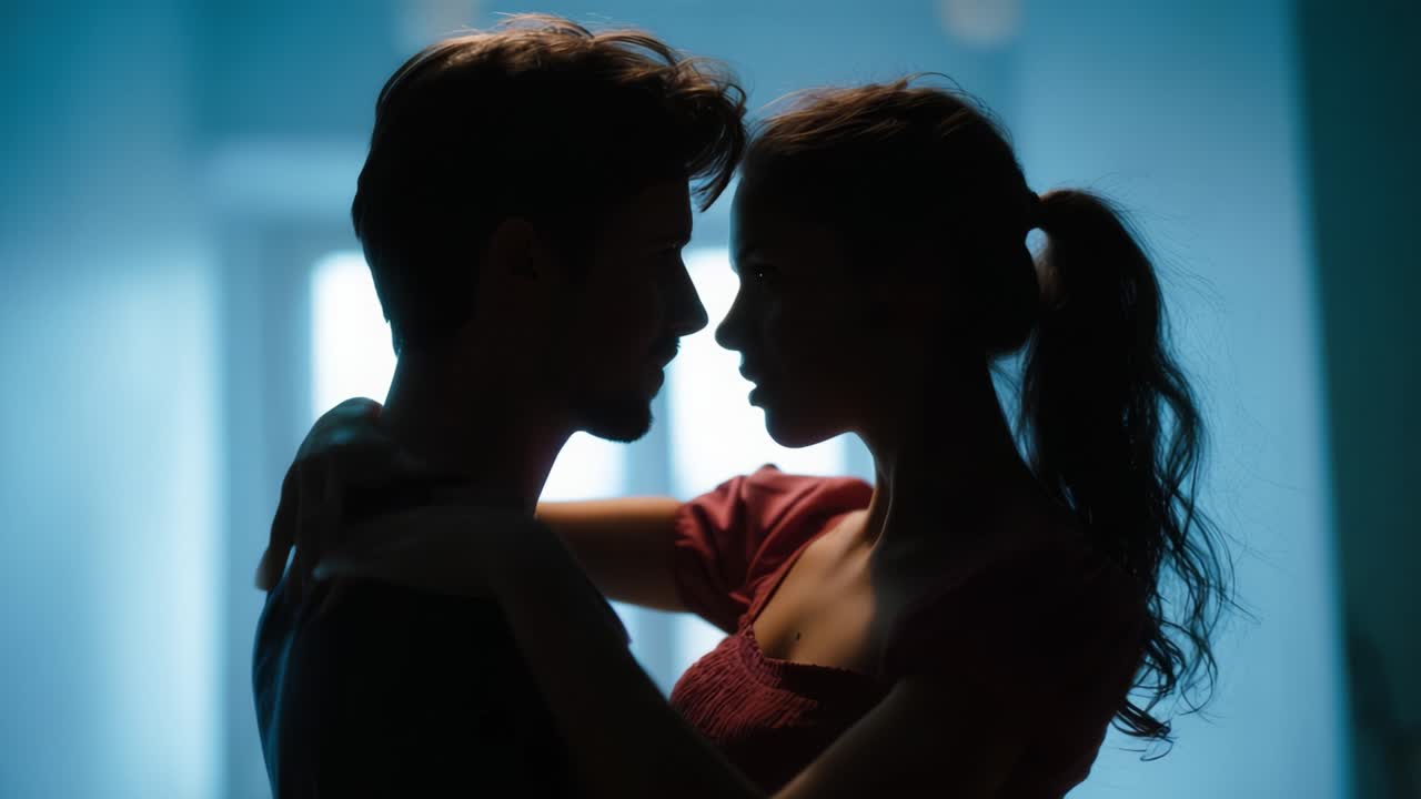 A tender moment shared between two people, captured in silhouette against a soft, blue background, evoking emotions of love, intimacy, and connection