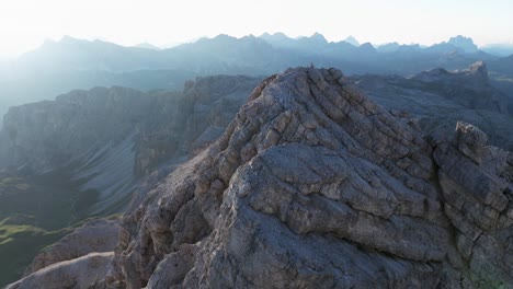 Una-Vista-De-Cerca-De-Los-Dolomitas-Muestra-Sus-Intrincadas-Capas-Y-Texturas-De-Roca,-Contrastadas-Con-Un-Telón-De-Fondo-De-Picos-Distantes-Bajo-Un-Cielo-Apagado.