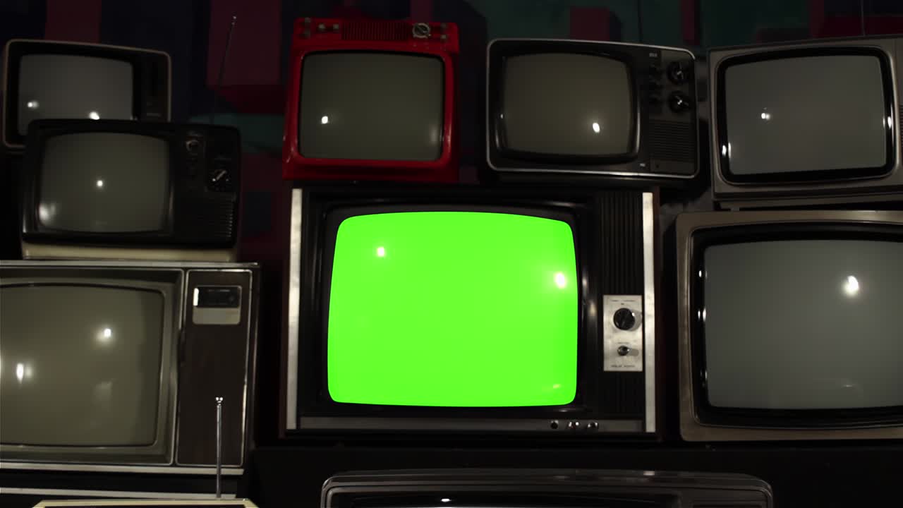 Gammelt tv med greenscreen omgivet af mange gamle tv-apparater. Dolly ud. 4K-opløsning