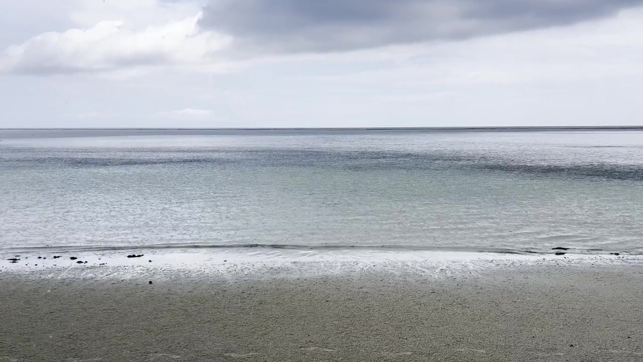 Rain falling on the sand and ocean water at Mtende Beach in Zanzibar, Tanzania