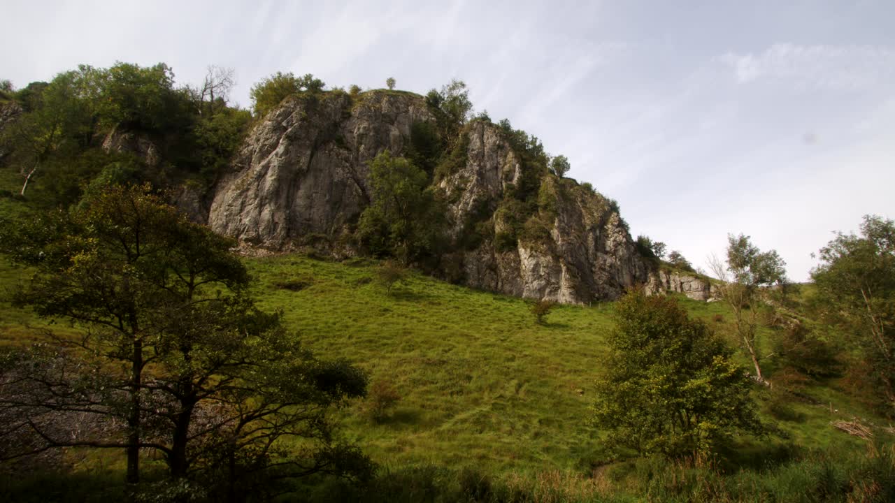 Ampia veduta che risale il percorso di Dove Dale, di un affioramento roccioso, uno sperone e una parete di roccia