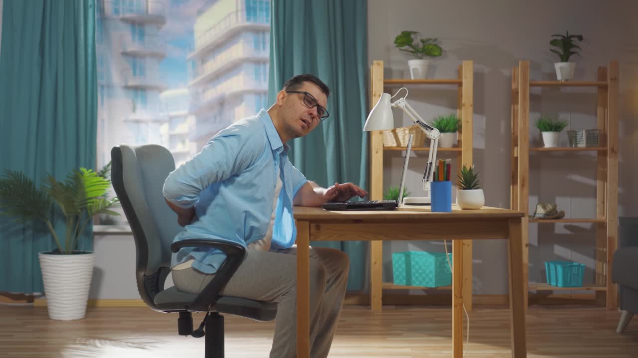 a male office worker or freelancer is sitting on a chair and experiencing back pain