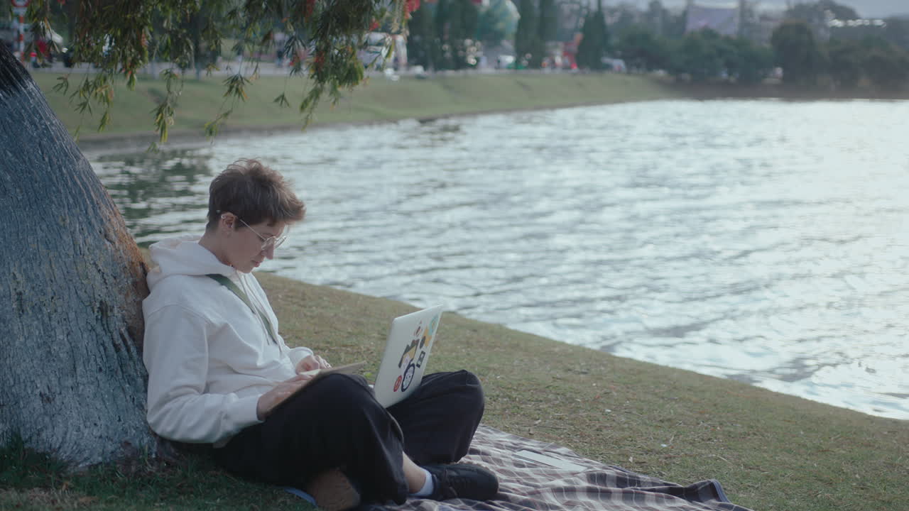 College Girl Studying with Laptop and Making Notes in the Park
