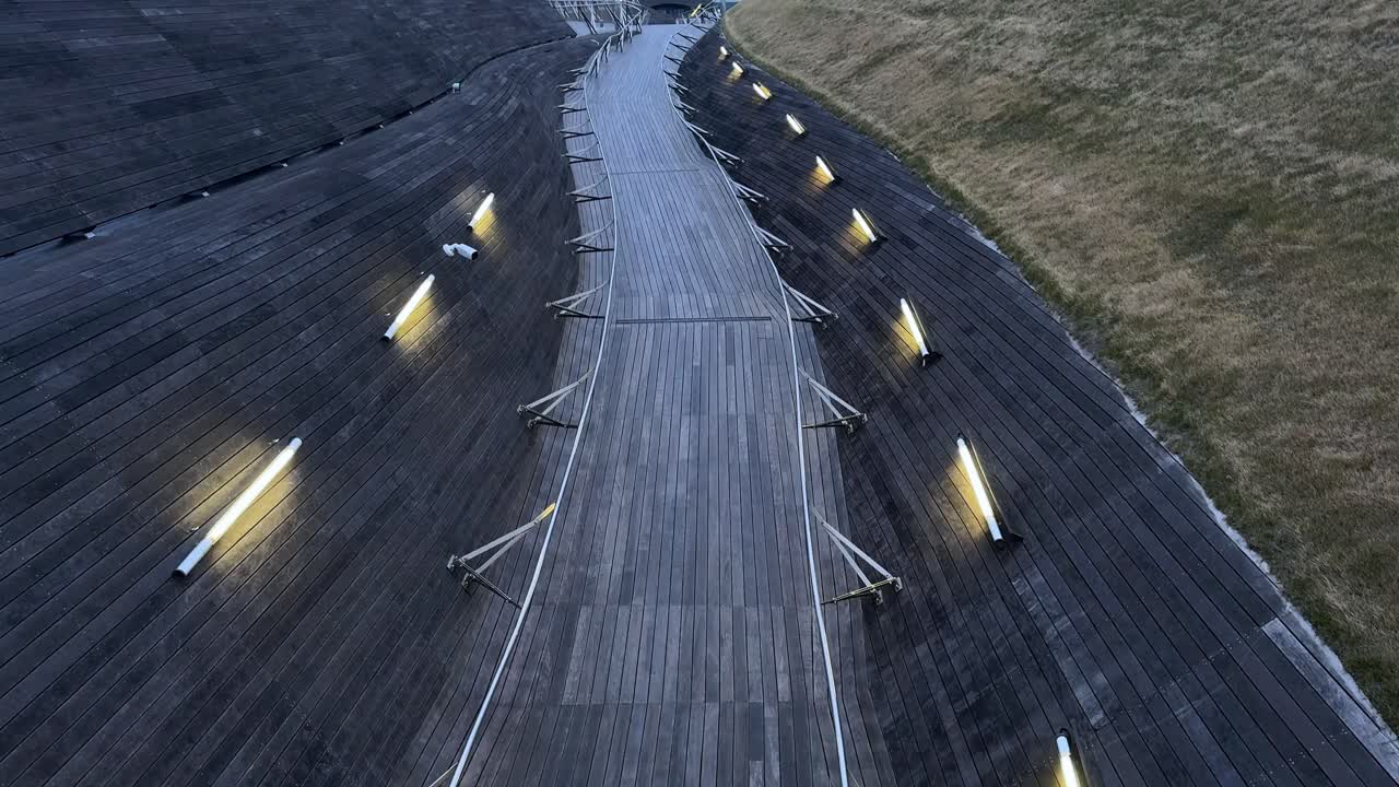 Empty wooden pier with lights at dusk, serene and tranquil, aerial view