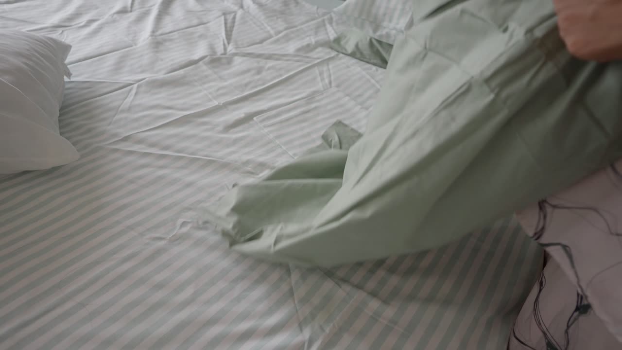 Person Changing a Pillowcase on a Striped Bed