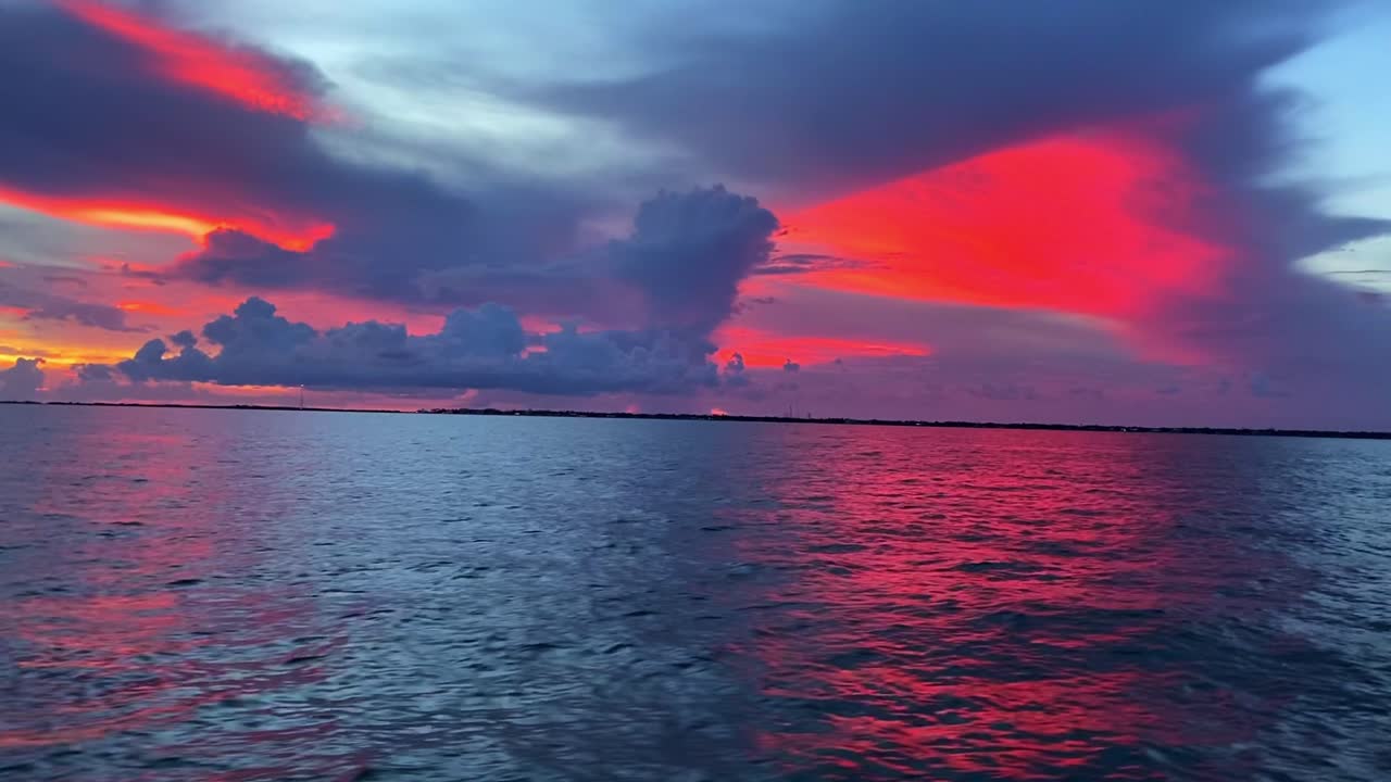 clip de puesta de sol en los cayos de florida, ee.uu., que revela las nubes y el cielo de color rojo sobre el océano en calma