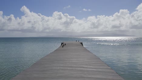 Camera-advances-on-sunny,-cloudy-day-along-aged-concrete-pier