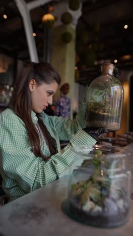 mujer examinando terrarios en un café