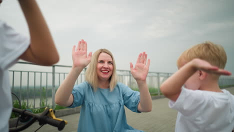 a joyful moment unfolds as a mother and her children try to give each other high fives, filled with laughter and playfulness